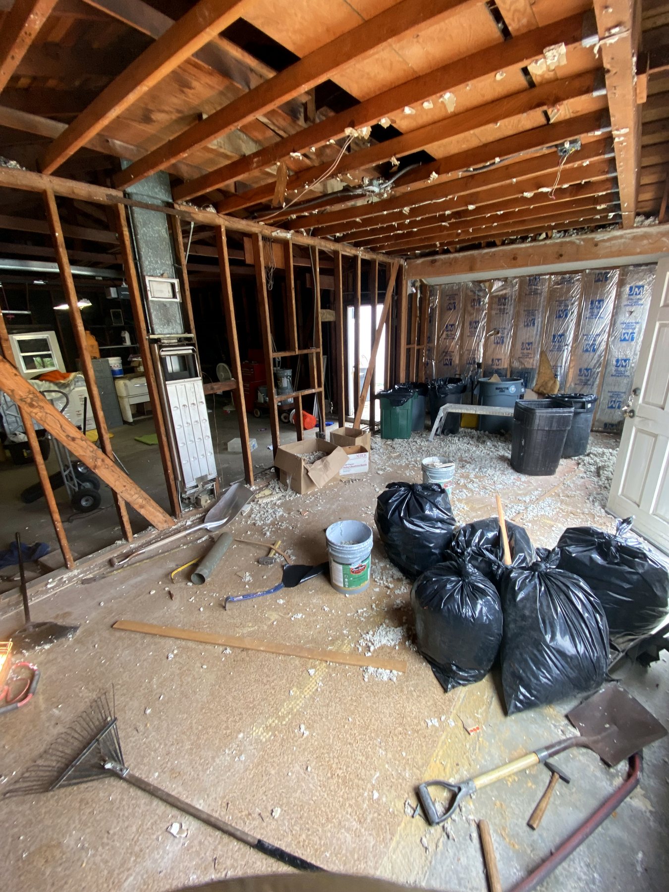 Open wood framing with demolition bags and tools during residential construction
