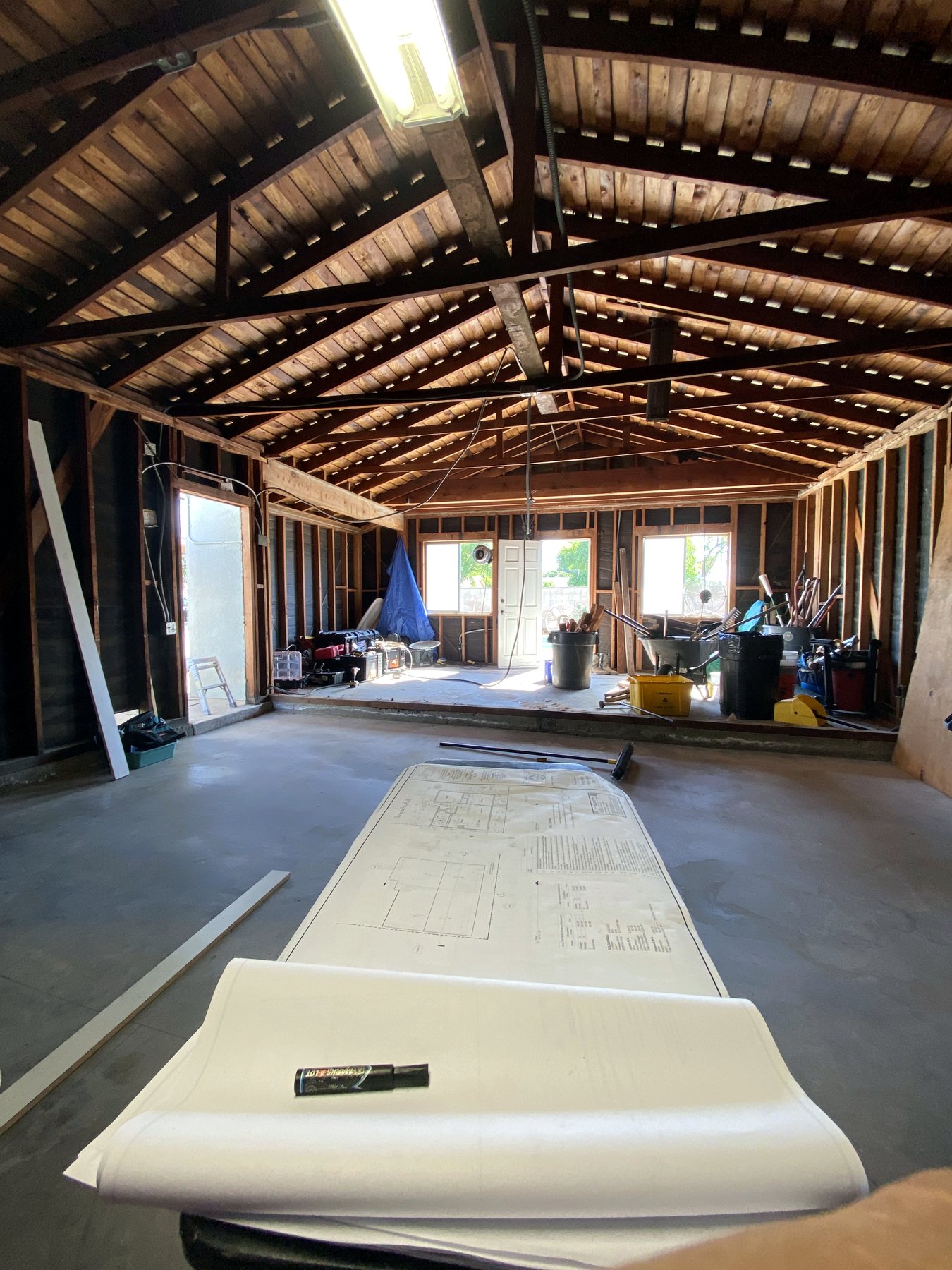 Rolled plans on a jobsite table inside an open framed residential space