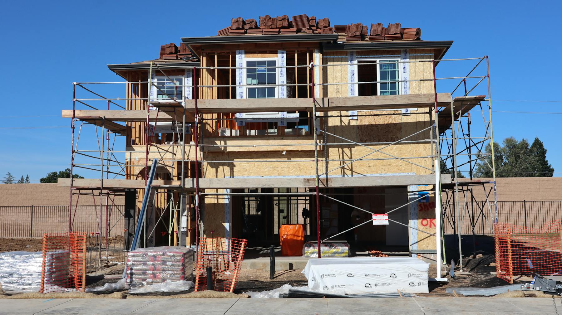 Residential exterior under construction with scaffolding and roof work
